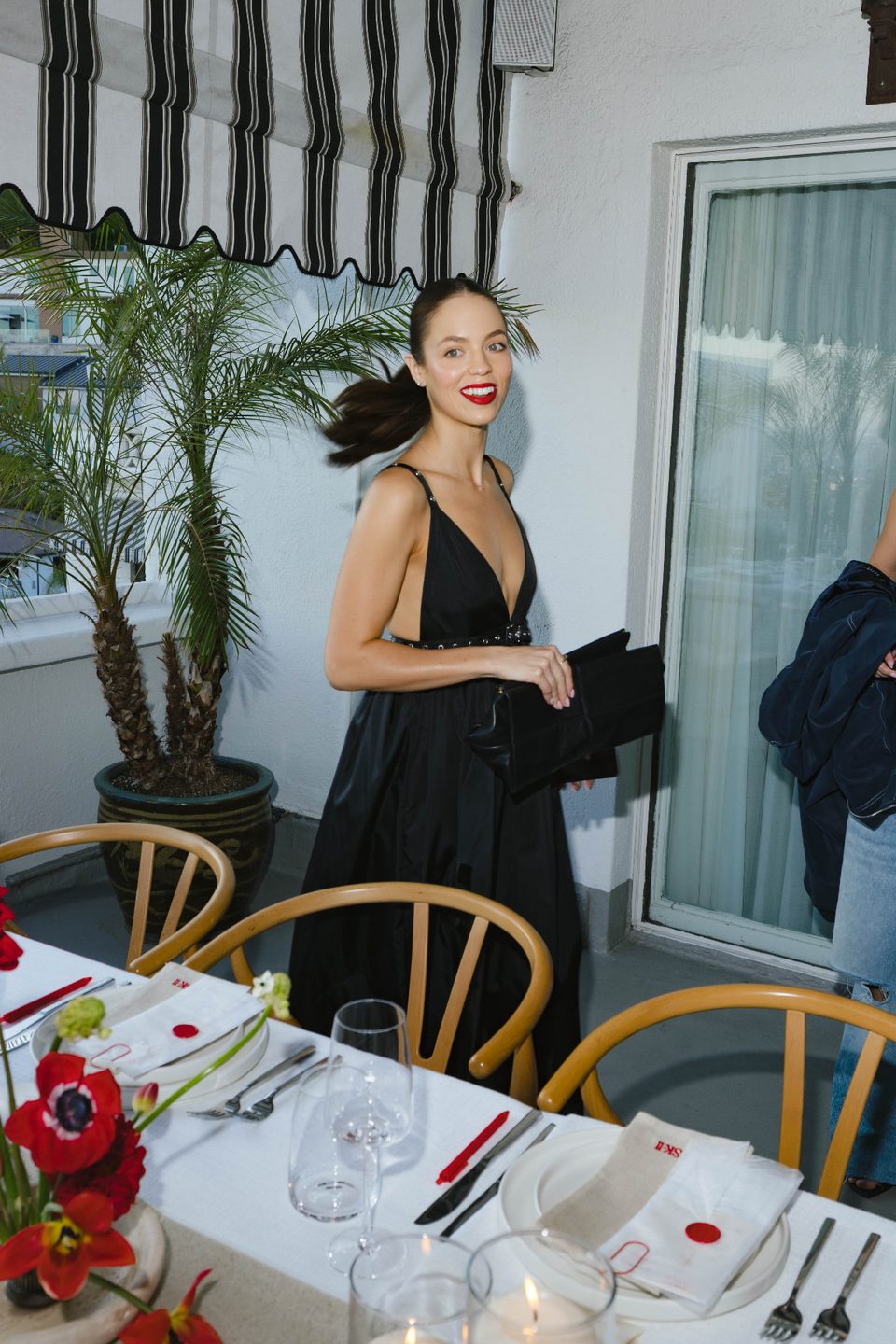 Creator in a black gown on a balcony beside a set dinner table